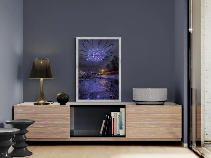 A luminous wire-flower sculpture glows with violet lights against a dark, moody night sky.